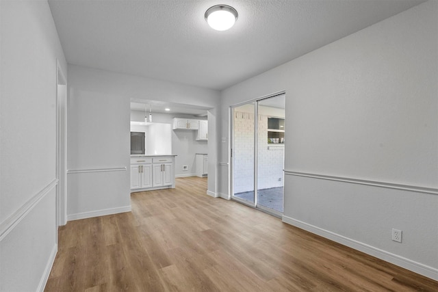 unfurnished living room featuring a textured ceiling and light hardwood / wood-style flooring