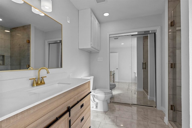 bathroom with tile patterned floors, vanity, toilet, and a shower with door