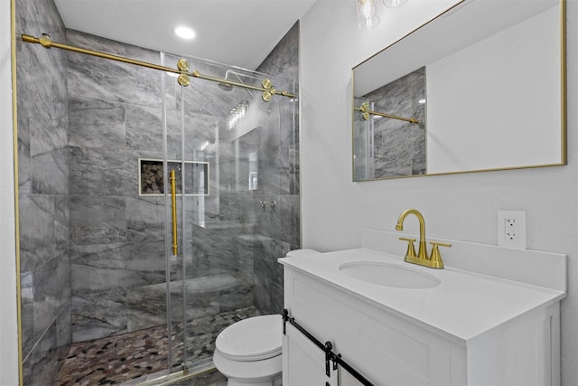 bathroom featuring vanity, a shower with shower door, and toilet