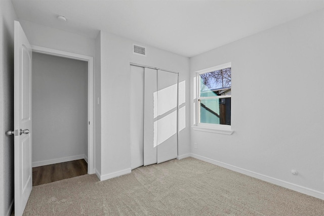 unfurnished bedroom featuring light carpet and a closet