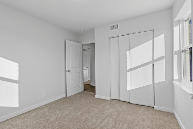 unfurnished bedroom featuring a closet, light carpet, and multiple windows