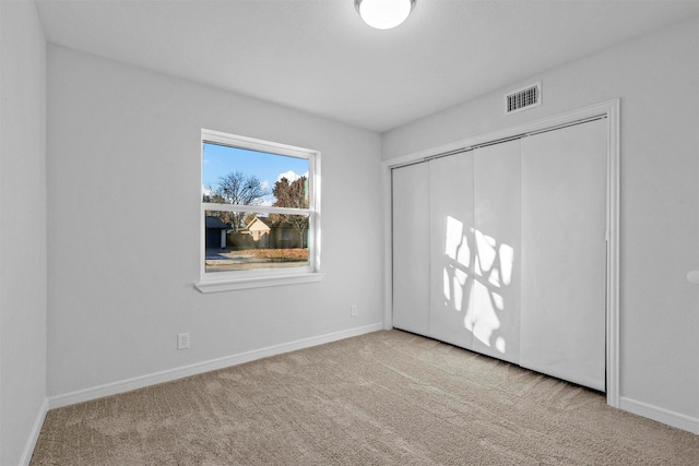 unfurnished bedroom featuring a closet and light colored carpet