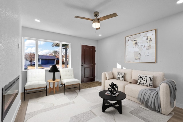 living area with heating unit, recessed lighting, ceiling fan, wood finished floors, and baseboards