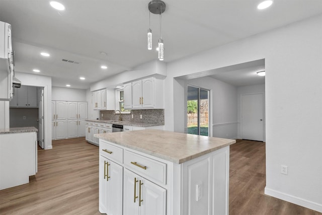 kitchen with decorative backsplash, sink, pendant lighting, hardwood / wood-style flooring, and white cabinets