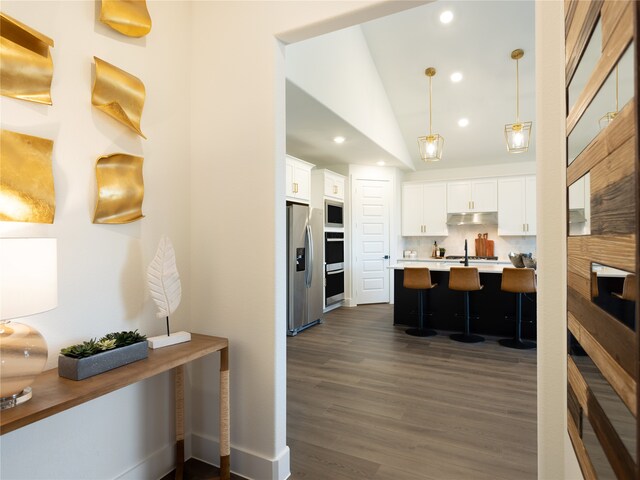 kitchen featuring backsplash, white cabinets, hanging light fixtures, and stainless steel appliances