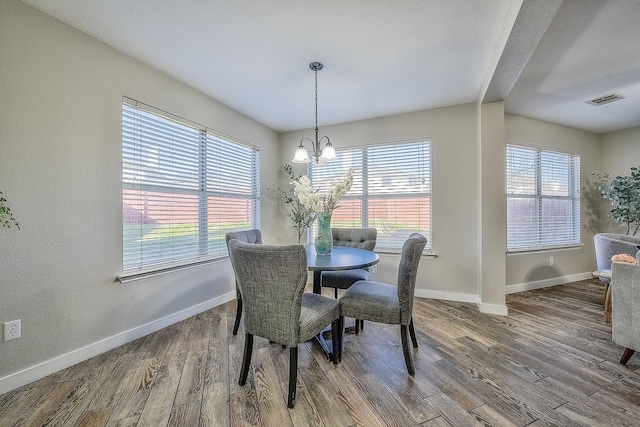 dining area with dark wood-type flooring and a chandelier