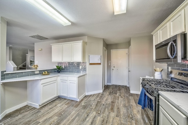 kitchen featuring appliances with stainless steel finishes, dark hardwood / wood-style floors, white cabinets, and backsplash