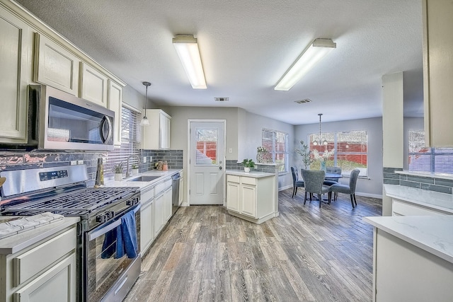 kitchen featuring pendant lighting, stainless steel appliances, and hardwood / wood-style floors