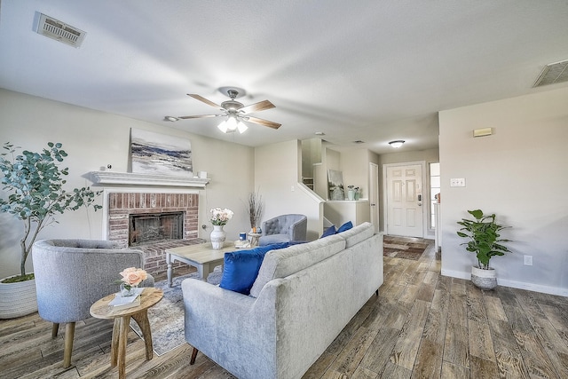 living room with ceiling fan, dark hardwood / wood-style floors, a textured ceiling, and a fireplace