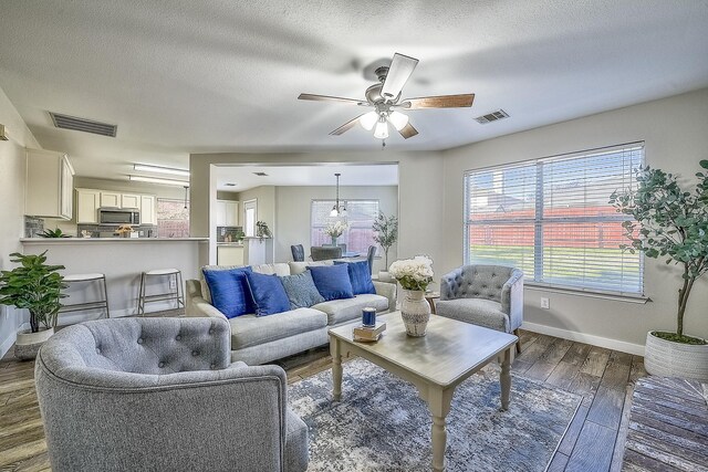 living room featuring ceiling fan, dark hardwood / wood-style flooring, and a textured ceiling