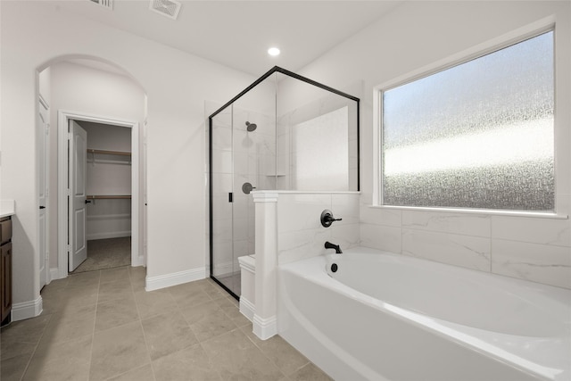 full bathroom featuring vanity, a garden tub, visible vents, a walk in closet, and a shower stall