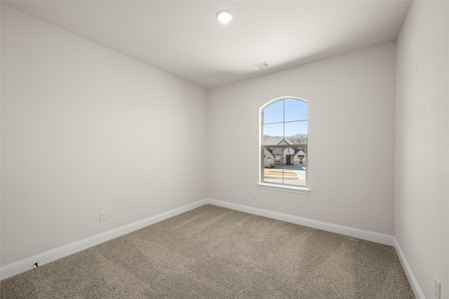 empty room with carpet floors, baseboards, and visible vents