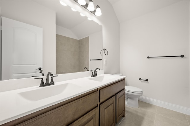 bathroom with tile patterned floors, vaulted ceiling, vanity, and toilet