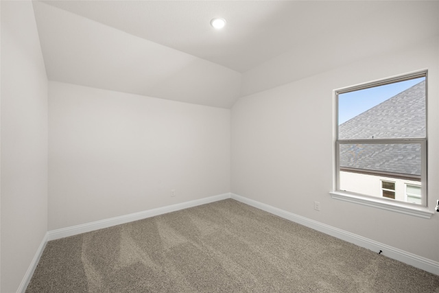 carpeted spare room with vaulted ceiling