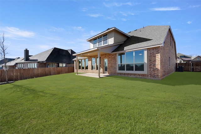 rear view of property featuring a fenced backyard, a patio, a lawn, and brick siding