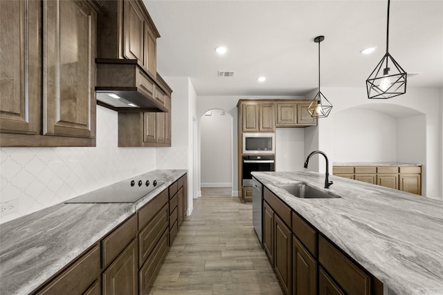 kitchen featuring tasteful backsplash, stainless steel appliances, light stone counters, pendant lighting, and sink