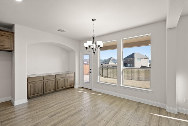 unfurnished dining area featuring light wood-type flooring and an inviting chandelier