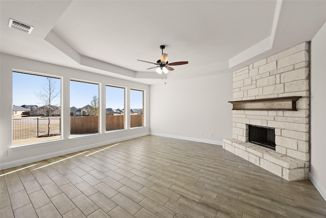 unfurnished living room featuring a fireplace, ceiling fan, a raised ceiling, and hardwood / wood-style flooring