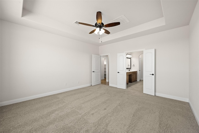 unfurnished bedroom with a raised ceiling, baseboards, light carpet, and visible vents