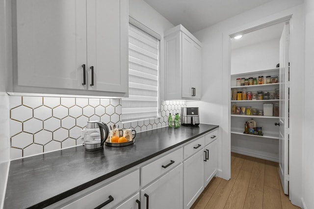 kitchen featuring white cabinetry, backsplash, and light hardwood / wood-style floors