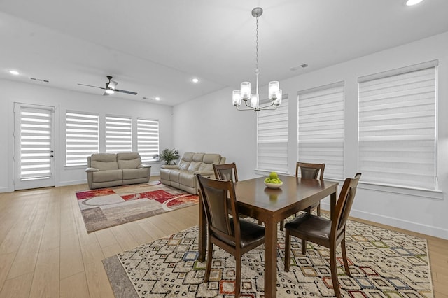 dining room with ceiling fan with notable chandelier and light hardwood / wood-style flooring