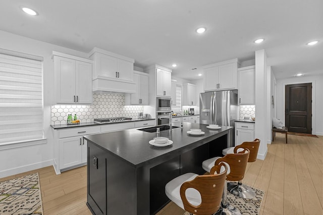 1208 Grass Hollow Pl, Celina, TX 75009 - kitchen featuring dark countertops, stainless steel appliances, light wood-style floors, an island with sink, and recessed lighting