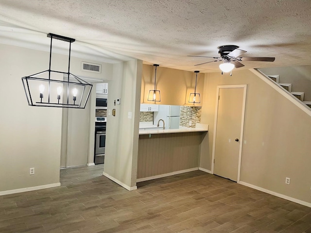 kitchen with decorative backsplash, pendant lighting, white appliances, and a textured ceiling