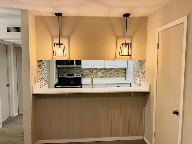 kitchen featuring decorative backsplash, pendant lighting, a textured ceiling, and appliances with stainless steel finishes