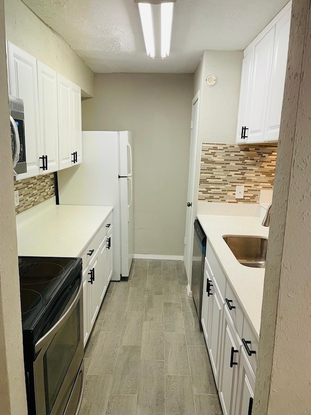 kitchen with decorative backsplash, appliances with stainless steel finishes, a textured ceiling, sink, and white cabinets