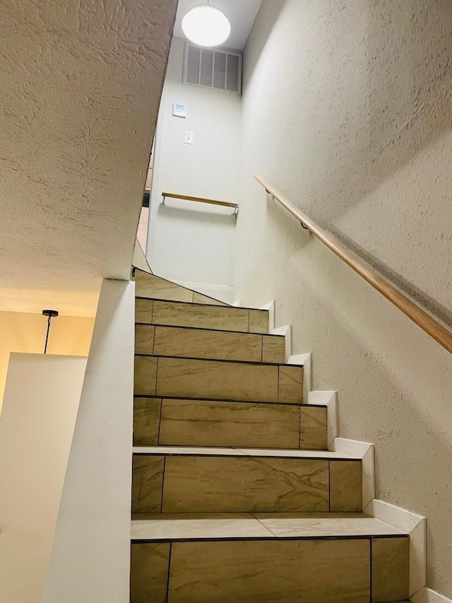 staircase with a textured ceiling