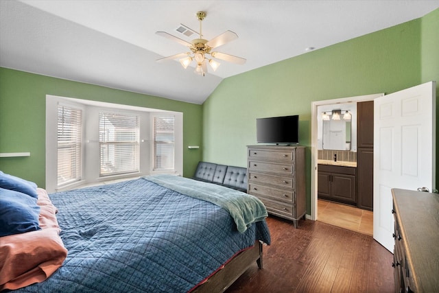 bedroom with dark hardwood / wood-style flooring, ceiling fan, connected bathroom, and lofted ceiling