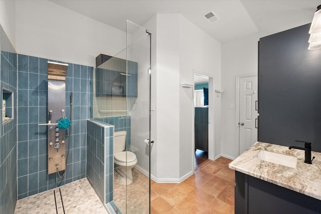 bathroom featuring toilet, vanity, tile patterned flooring, and tiled shower