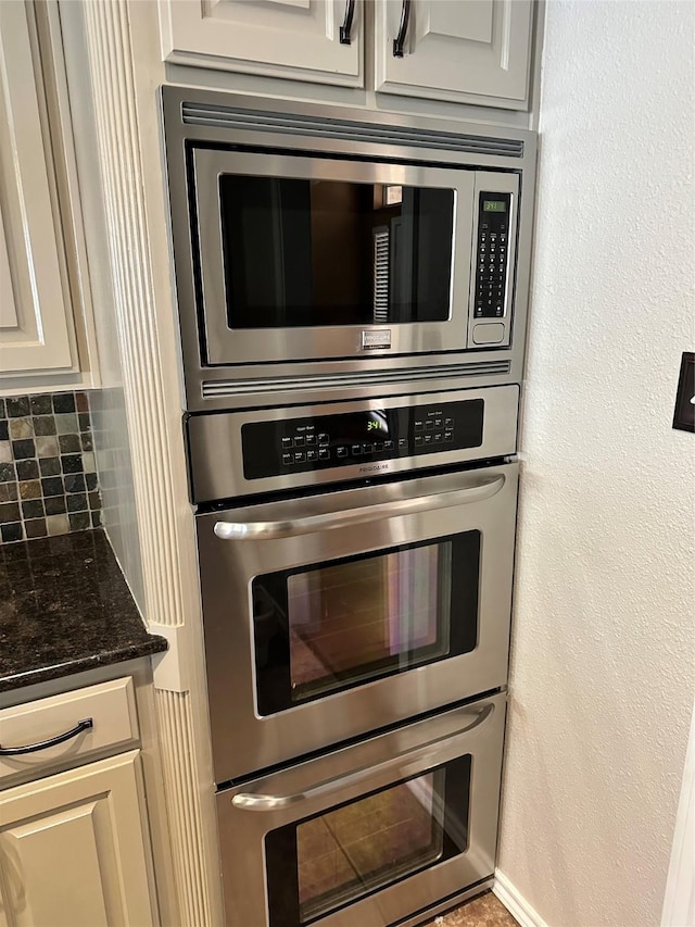 kitchen with stainless steel appliances, tasteful backsplash, and dark stone countertops