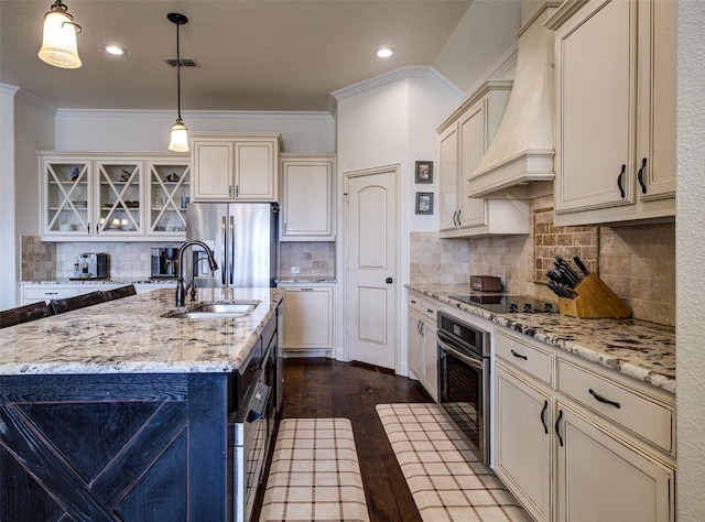 kitchen with custom exhaust hood, a center island with sink, appliances with stainless steel finishes, hanging light fixtures, and sink