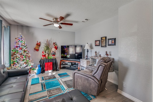 living room with light wood-type flooring, a textured ceiling, and ceiling fan