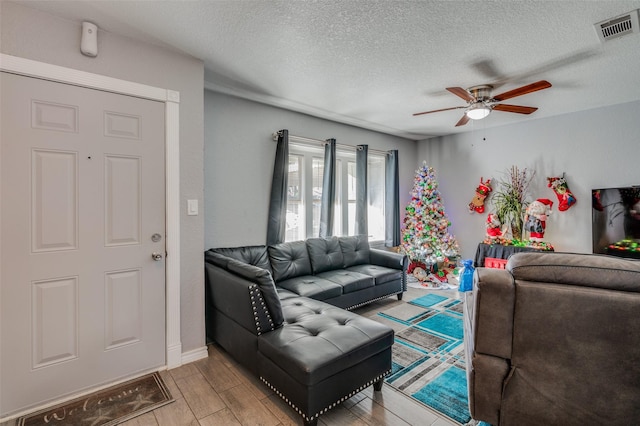 living room with ceiling fan, light hardwood / wood-style flooring, and a textured ceiling