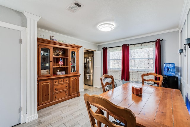 dining space featuring decorative columns, light hardwood / wood-style flooring, and crown molding