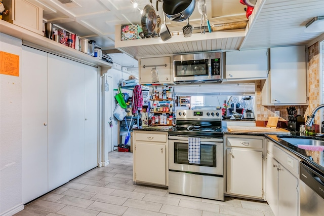 kitchen with sink, decorative backsplash, dark stone countertops, white cabinetry, and stainless steel appliances