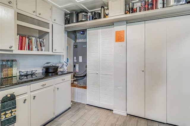 kitchen with white cabinets, light hardwood / wood-style floors, and dark stone countertops