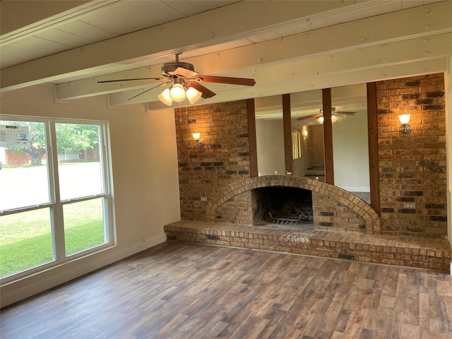 unfurnished living room featuring beam ceiling, hardwood / wood-style flooring, a brick fireplace, and ceiling fan