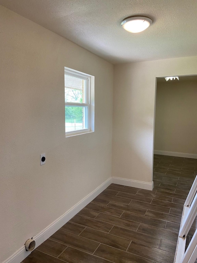 spare room featuring a textured ceiling and dark hardwood / wood-style floors