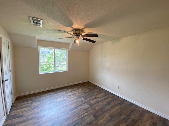 empty room with a textured ceiling, lofted ceiling, ceiling fan, and dark hardwood / wood-style floors