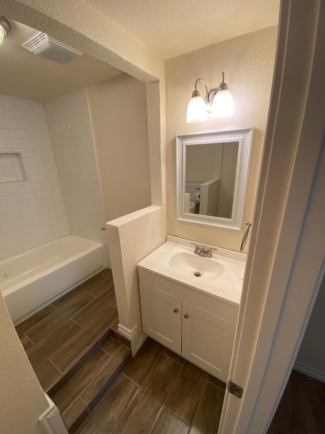 bathroom featuring vanity, tiled shower / bath combo, and a textured ceiling