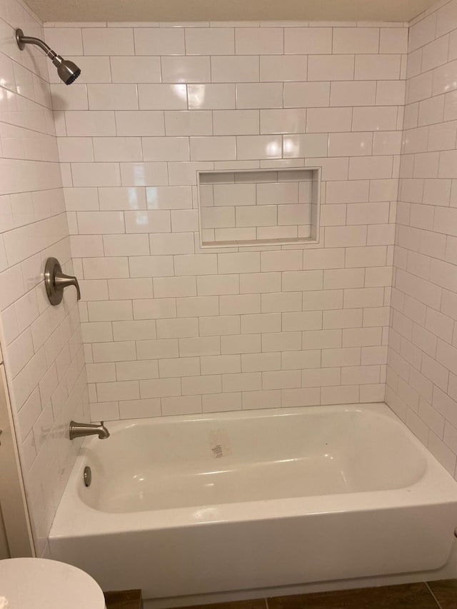 bathroom with tiled shower / bath combo and toilet