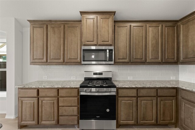 kitchen featuring backsplash, light stone countertops, and stainless steel appliances