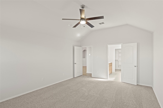 unfurnished bedroom with ensuite bath, ceiling fan, light colored carpet, and vaulted ceiling