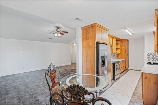 kitchen with vaulted ceiling, ceiling fan, a textured ceiling, tasteful backsplash, and stainless steel appliances