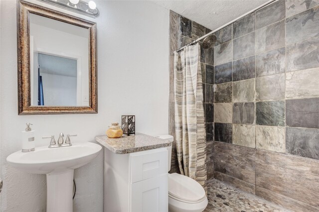 bathroom with toilet, curtained shower, and a textured ceiling