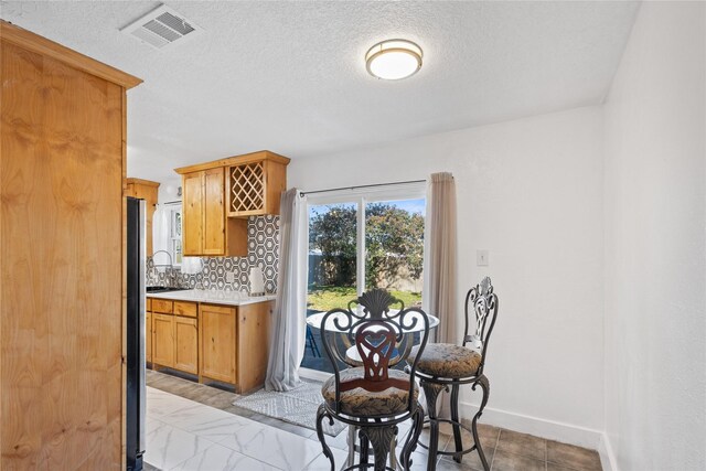 kitchen with stainless steel fridge, decorative backsplash, and a textured ceiling