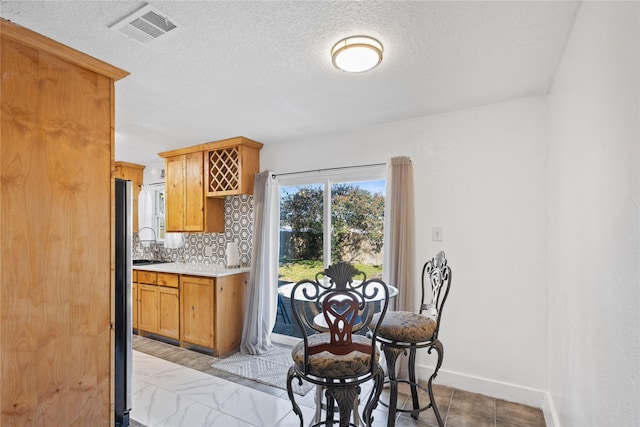 kitchen with tasteful backsplash, stainless steel fridge, and a textured ceiling